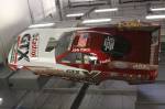 An old John Force flopper hangs above the dyno cell.  &raquo; Click to zoom ->