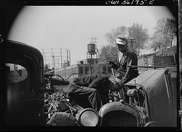 Two junkyard men taking a car apart