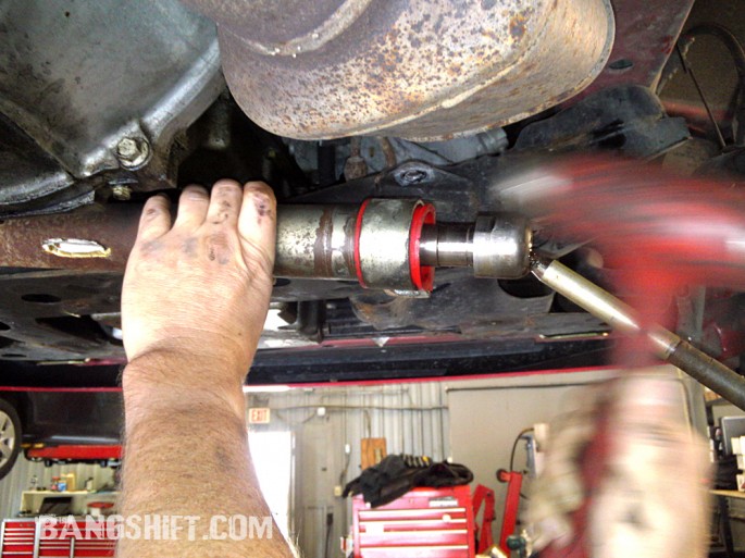 Dave taps the steering rack bushing and strap into place.